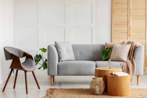Modern armchair next to a sofa and wooden coffee tables in a living room interior