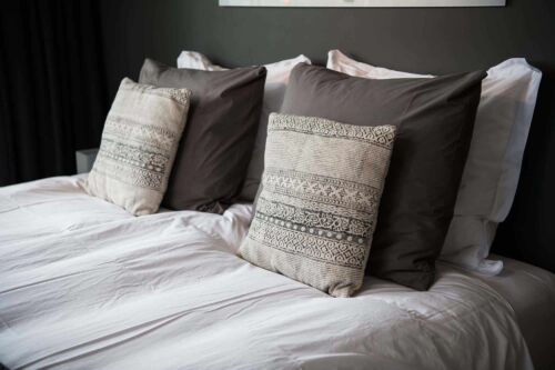 Gray color scheme pillows setting on bed with satin finished style bedding.